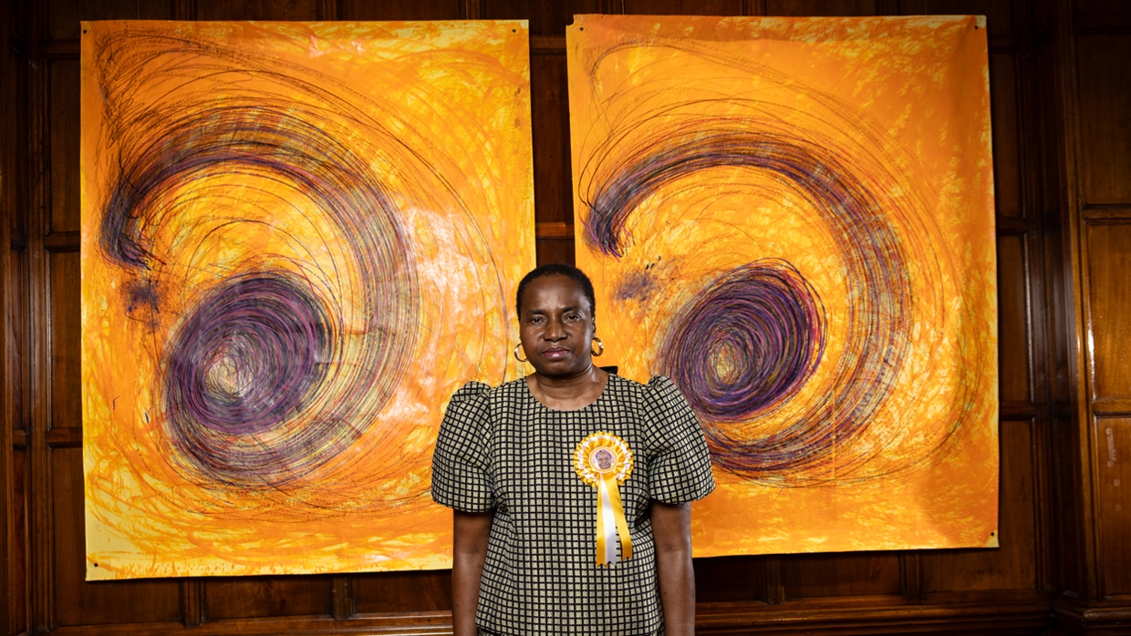 Nnena Kalu standing in front of her artwork facing the camera 