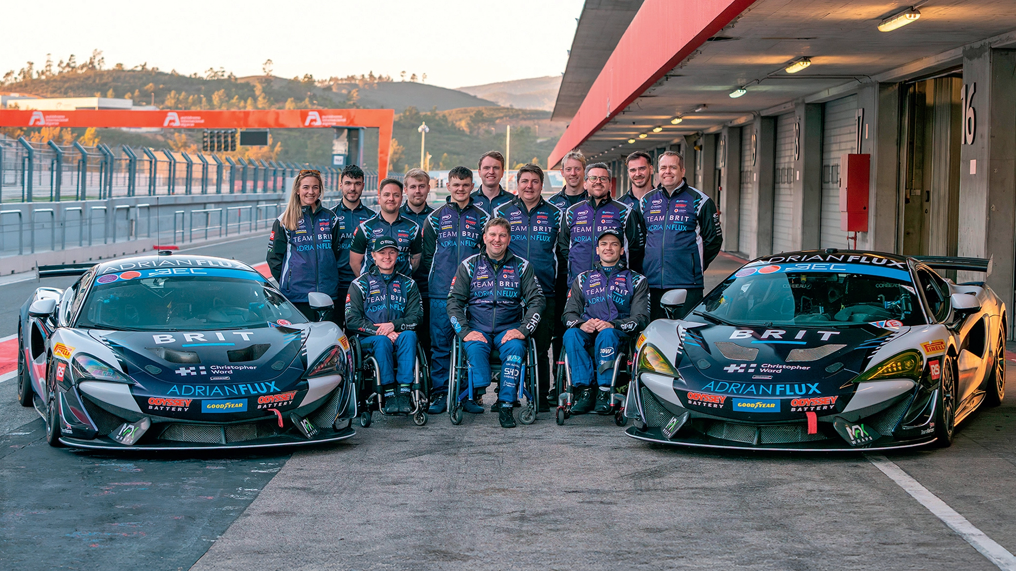 Team BRIT standing between two cars smiling at the camera