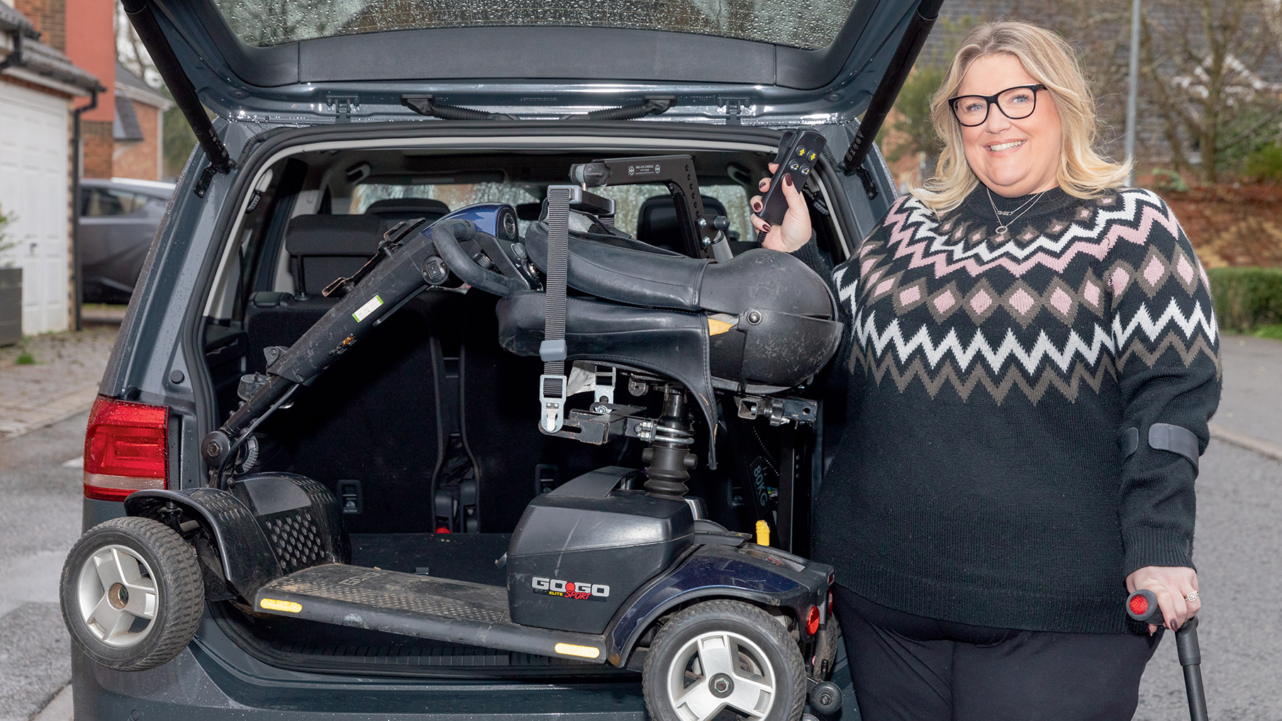 Kerry Riches smiling next to her car holding her walking stick
