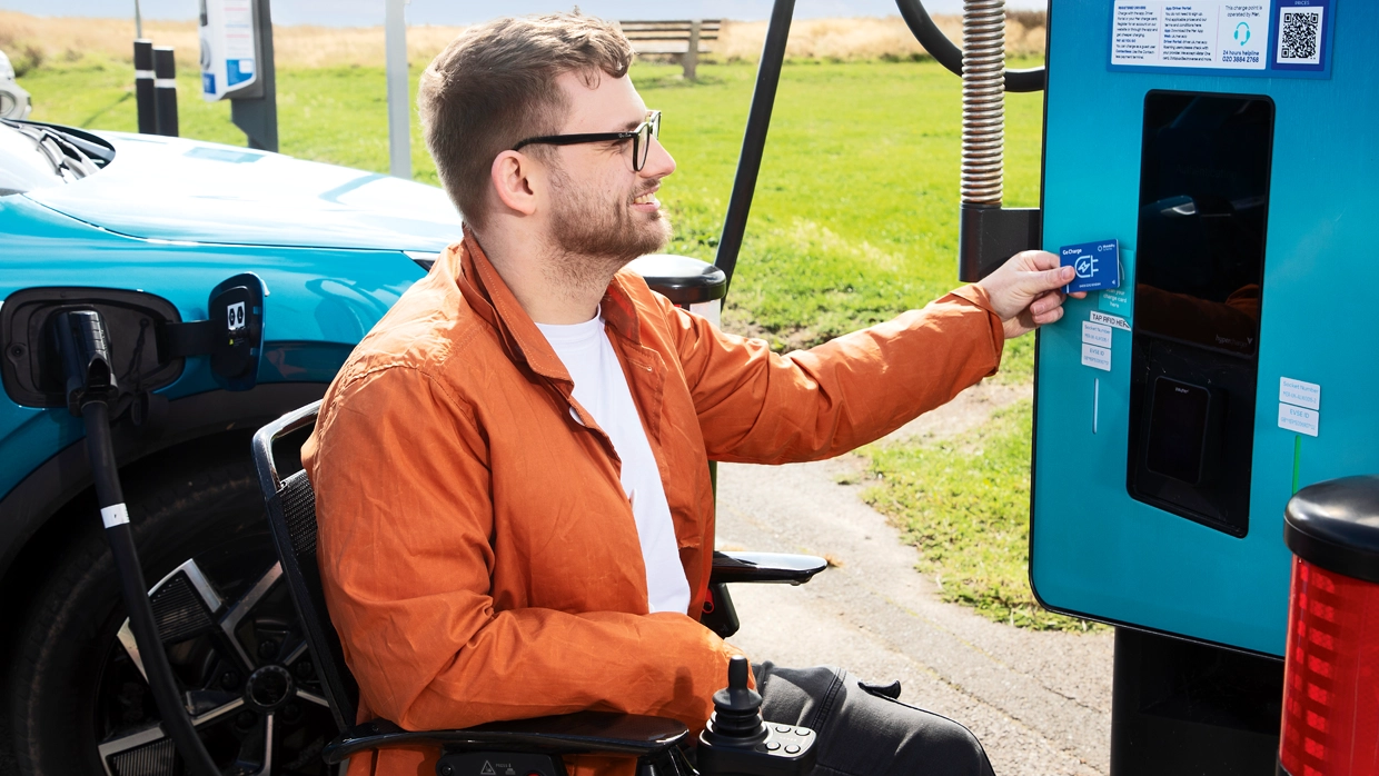 A male wheelchair user using a electric vehicle fast chargepoint