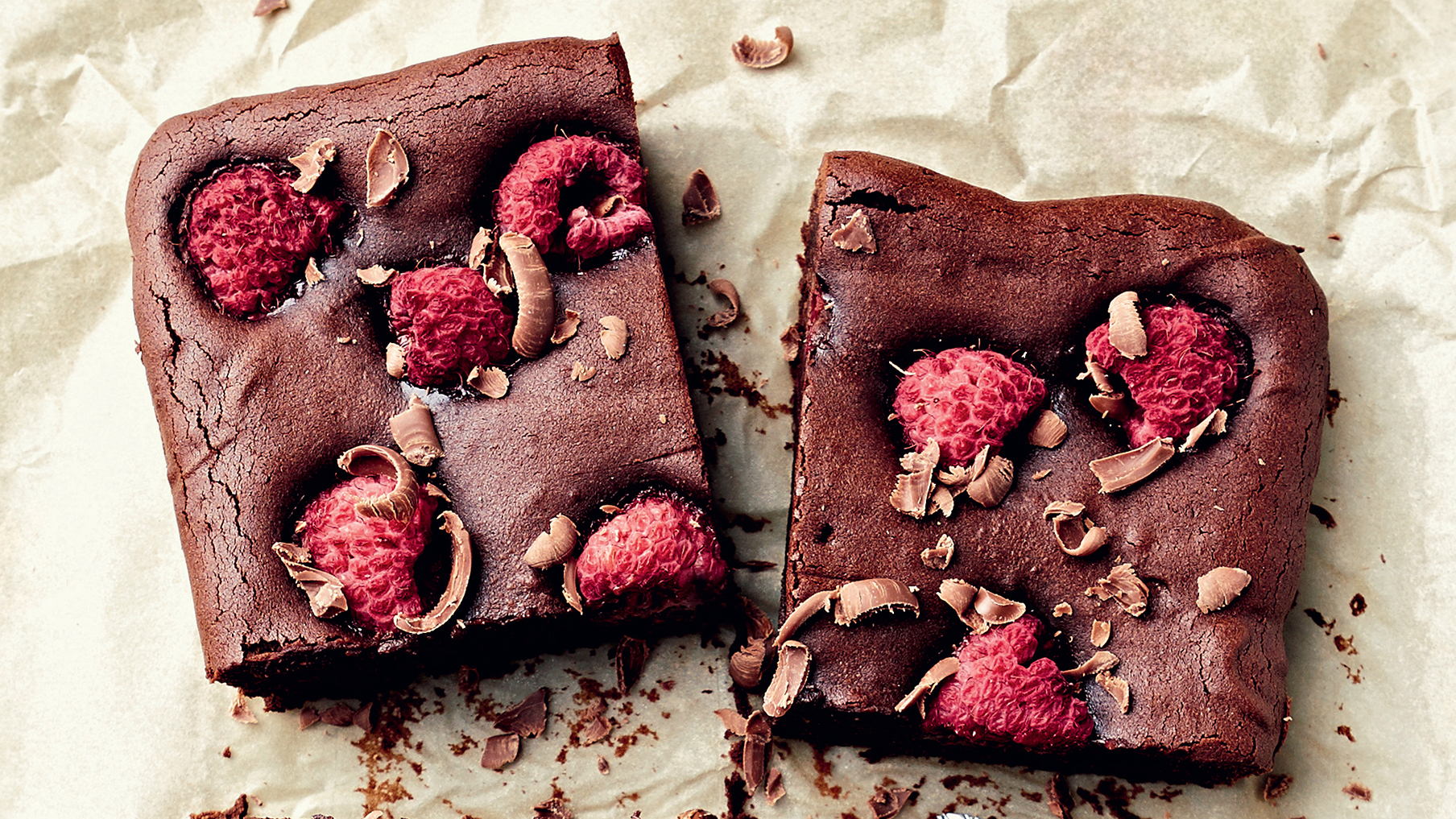 A picture of chocolate brownies with raspberries on cooking paper 